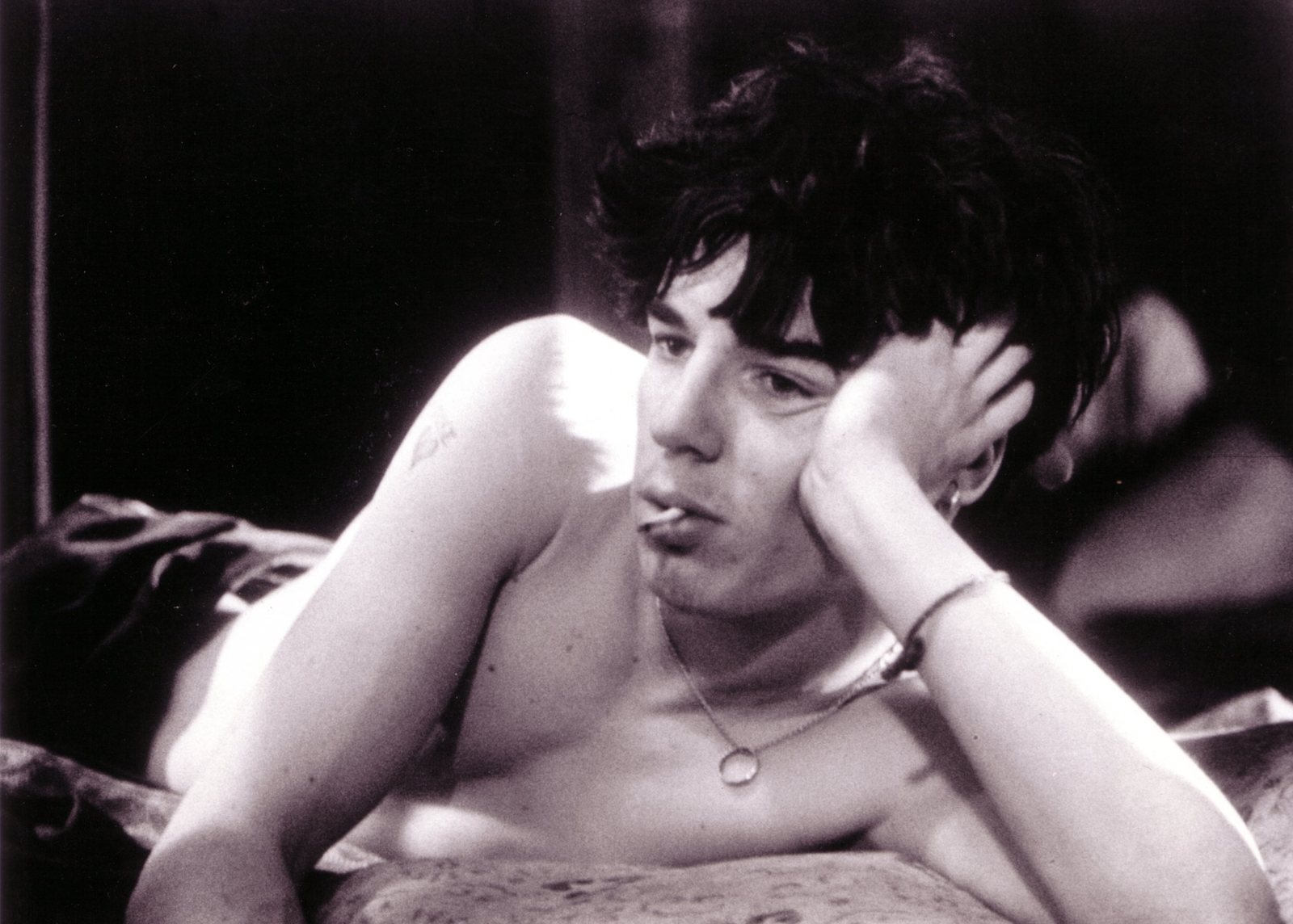Charlie Creed-Miles as David, lying on a bed with a cigarette, black and white