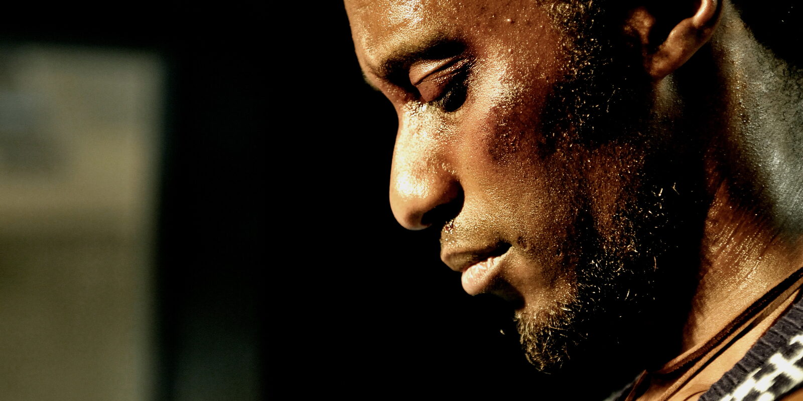 Delroy with his head bowed, in shadow