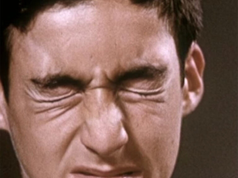 Close-up of a young man screwing his face up