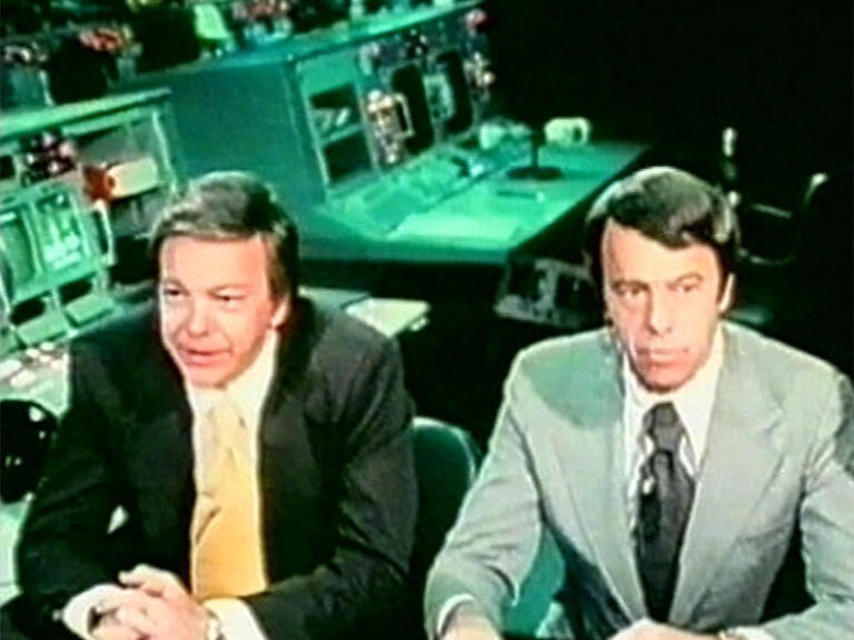 Two 1970s presenters at a television control desk