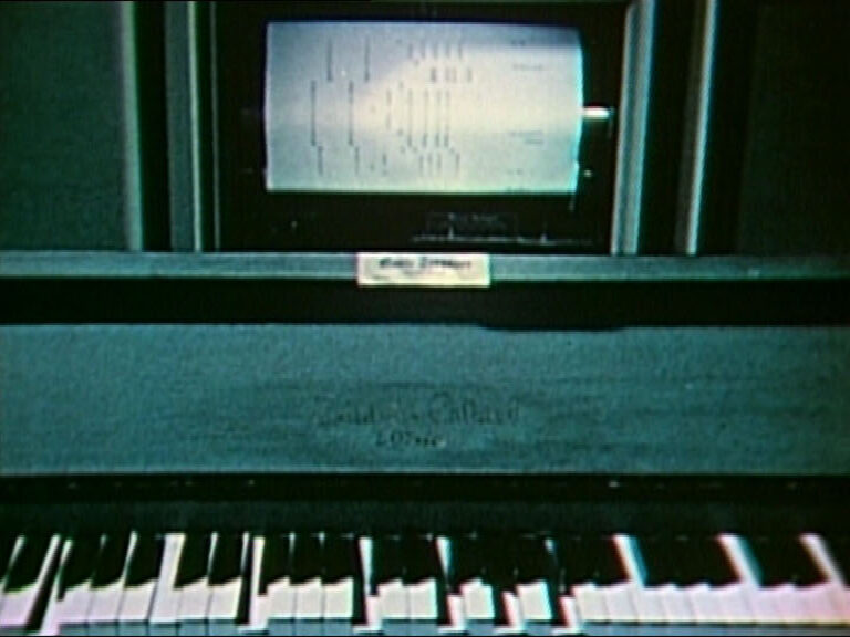 A computer screen mounted above an electronic organ keyboard
